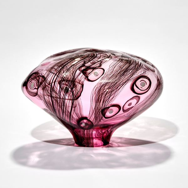 smooth surfaced simplified mushroom shaped sculpture handmade from pink transparent glass with dark aubergine line and circle patterns with white dots