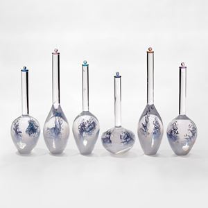 five glass bottles with bulbous white bottoms fading to clear in their long thin necks each containing a blue helix line detail and all with coloured stopper in different colours