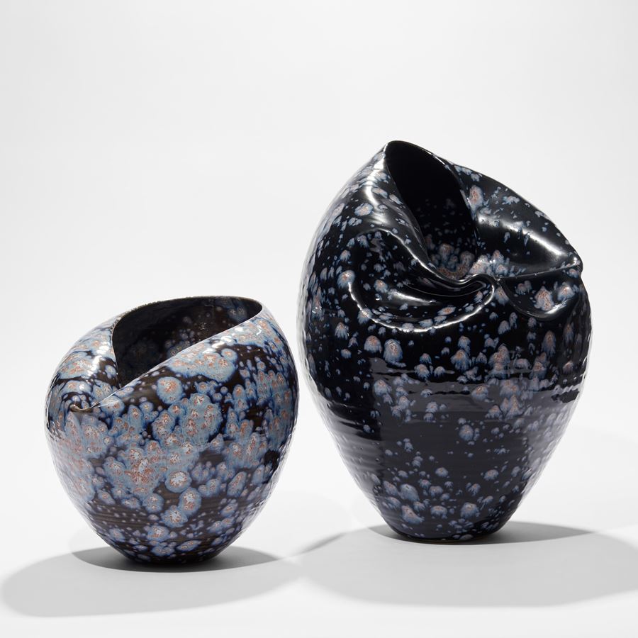 rounded vase with collapsed inverted top section in dark black blue with light blue white and pink starburst splodges hand thrown and glazed from ceramic