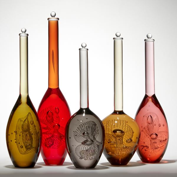 series of nine solid scientific looking bottle forms in various transparent warm colours sea green amber orange red bronze gold peach and grey each with a spiralling helix detail inside hand made from glass