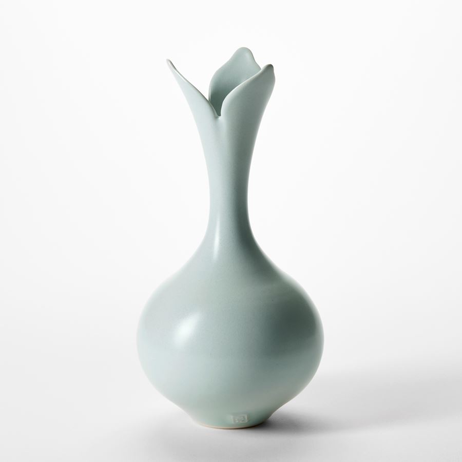 trio of celadon glazed elegant porcelain vases with round bases sweeping flaring necks and opening rims with floral cut petal details