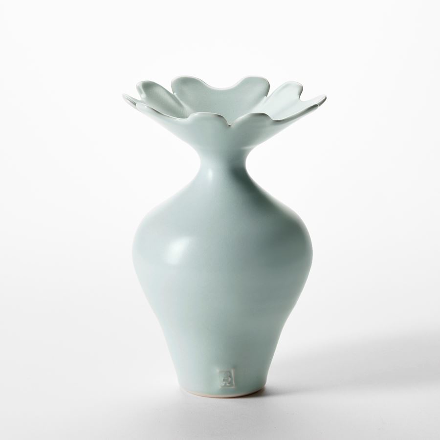 trio of celadon glazed elegant porcelain vases with round bases sweeping flaring necks and opening rims with floral cut petal details