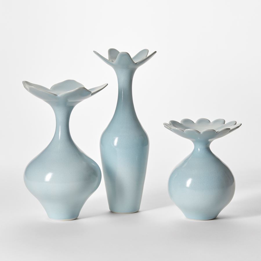 trio of soft pastel turquoise vases each with rounded bases tapering elegant necks and flared rims with scalloped simplified floral edges