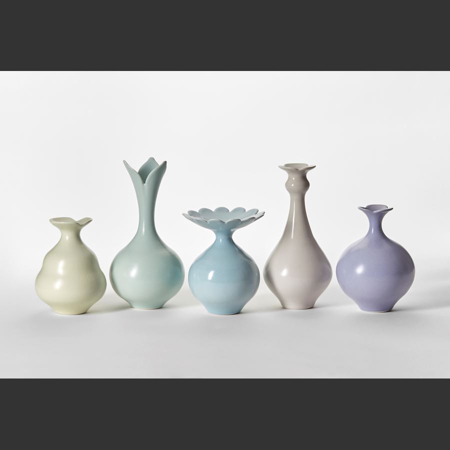 set of three porcelain vases in soft mauve purple each with a flared top neck with simple floral scalloped edges