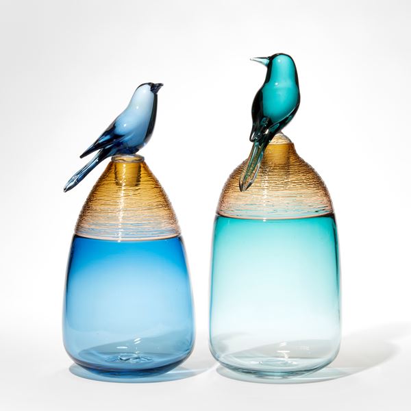 blue and amber bottle with stopper top adorned with a perched blue bird hand made from glass