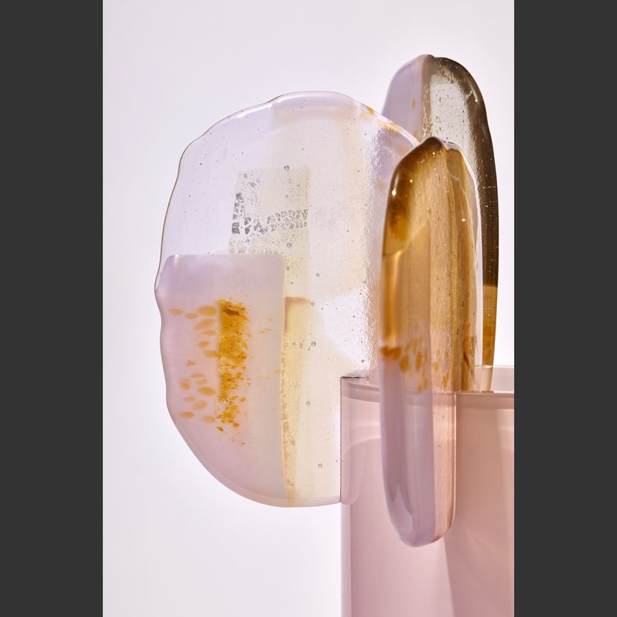 soft fading to the top opaque pink tall cylinder with five rounded finials perched on the top rim each with abstract patterns in yellow gold white and pink handmade from glass