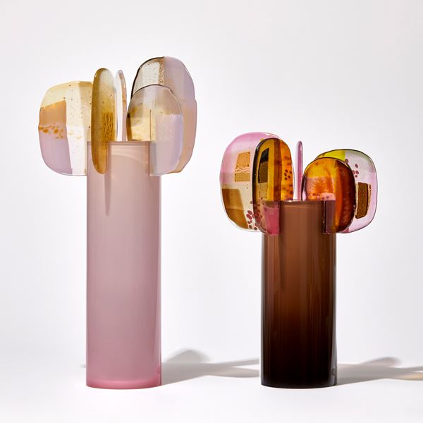soft fading to the top opaque pink tall cylinder with five rounded finials perched on the top rim each with abstract patterns in yellow gold white and pink handmade from glass