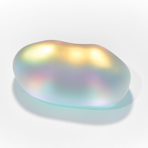 shimmering glass amorphic pebble rock sculpture with inner myriad of colours with the appearance as if emitting light from within hand made from blown and sculpted glass