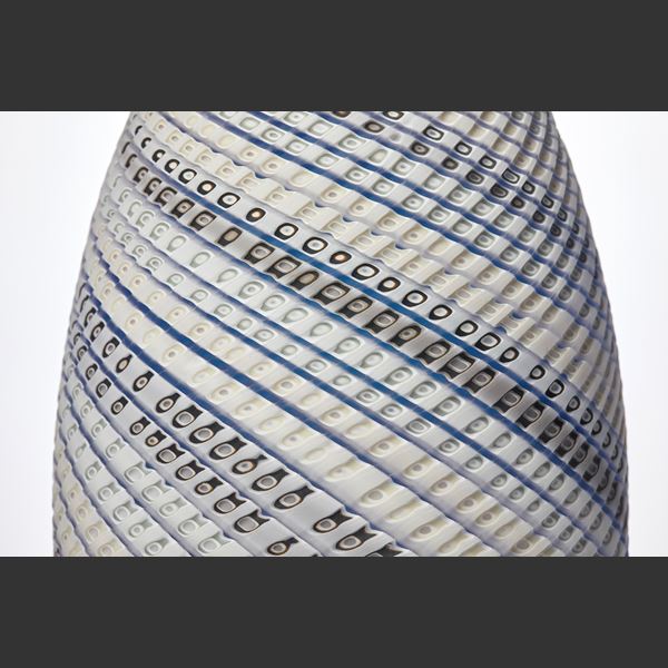 tall standing ovoid vessel with small opening at the top and curling lines round the form in white grey and soft blue with textured cut surface hand made from glass