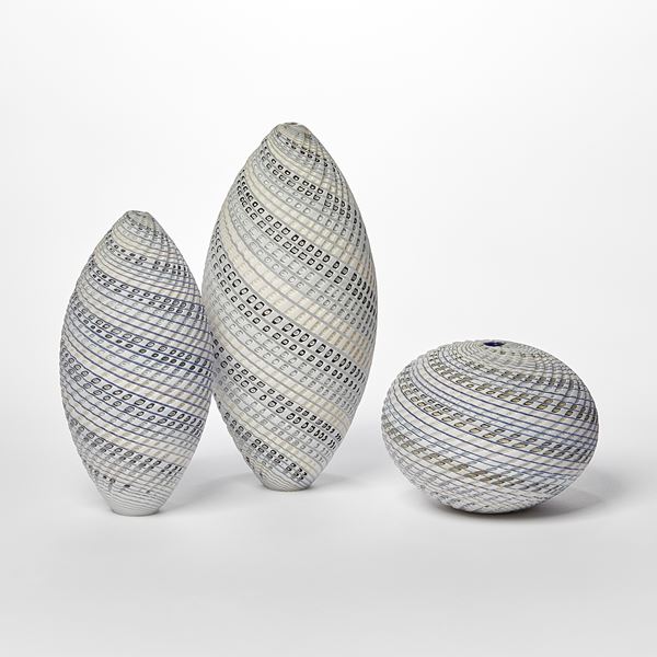 pointed standing ovoid shaped vessel with banded coloured and cut lines in white cream blue and grey twisting round the from hand made from glass