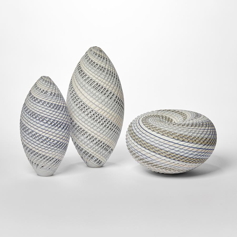 pointed standing ovoid shaped vessel with banded coloured and cut lines in white cream blue and grey twisting round the from hand made from glass