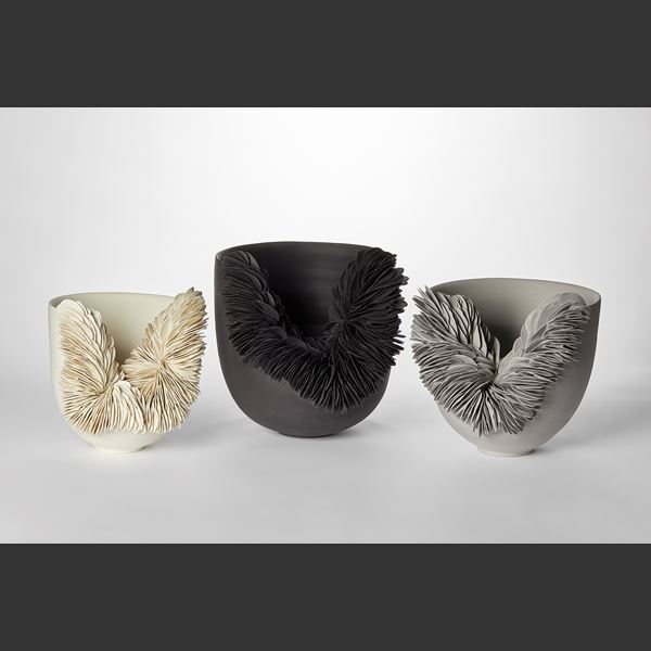 round black bowl with front side cut away and filled with stacked black rocky shards hand thrown from coloured porcelain