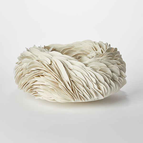 round off white creamy bowl covered in shards with a weather worn appearance and almost like irregular animal scales hand made from porcelain