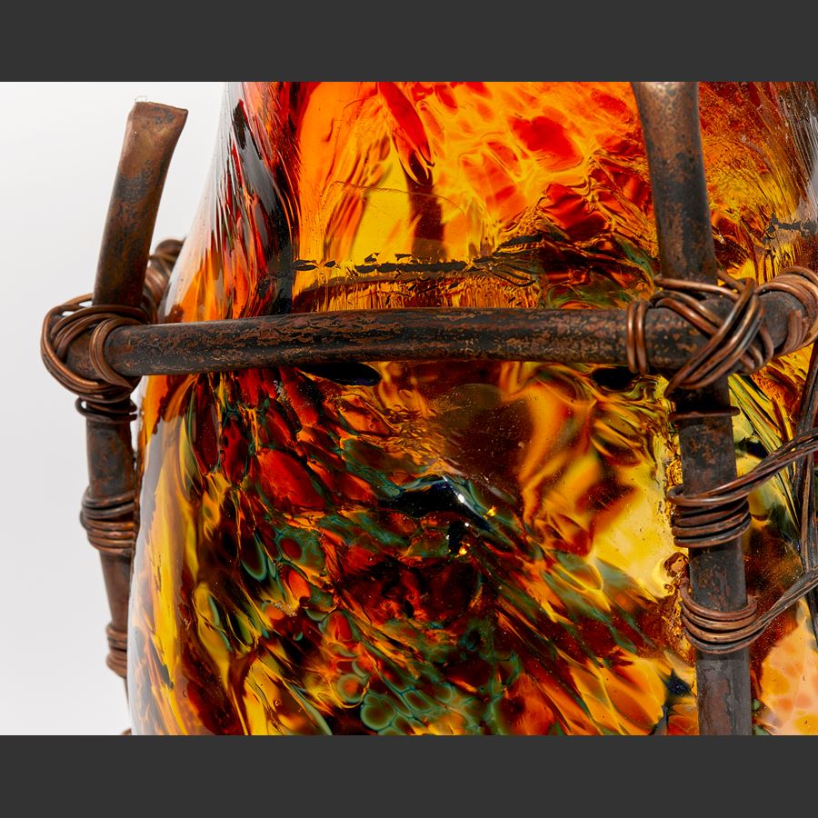 hand made transparent textured red and amber amorphic glass sculpture trapped within a square copper pipe and wire cage with bound rope top interlaced with copper manillas
