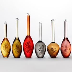 series of nine solid scientific looking bottle forms in various transparent warm colours sea green amber orange red bronze gold peach and grey each with a spiralling helix detail inside hand made from glass