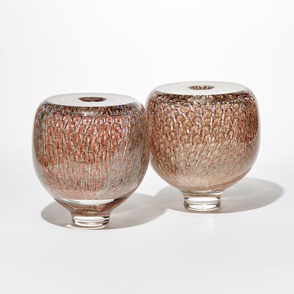 shiny transparent heavy round vessel with flat top and small central opening covered in an embedded fine repeat organic pattern in coral salmon aubergine and soft yellow hand made from glass