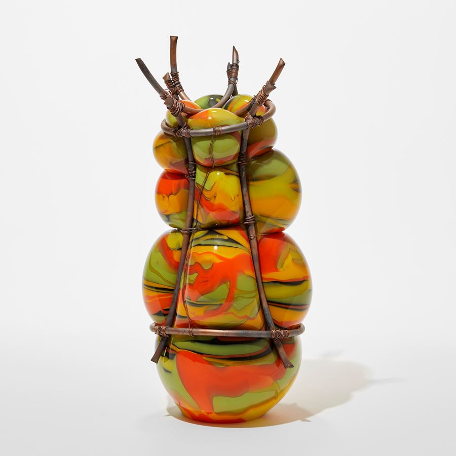 opaque lime green yellow red and black blown glass sculpture held within and bulging between a bound copper cage with top crown of copper tubes