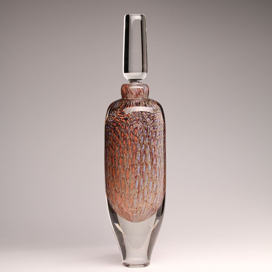 tall clear glass bottle with clear stopper and tapered clear base with trapped internally intense detailed repeat pattern in pale blue coral and soft orange