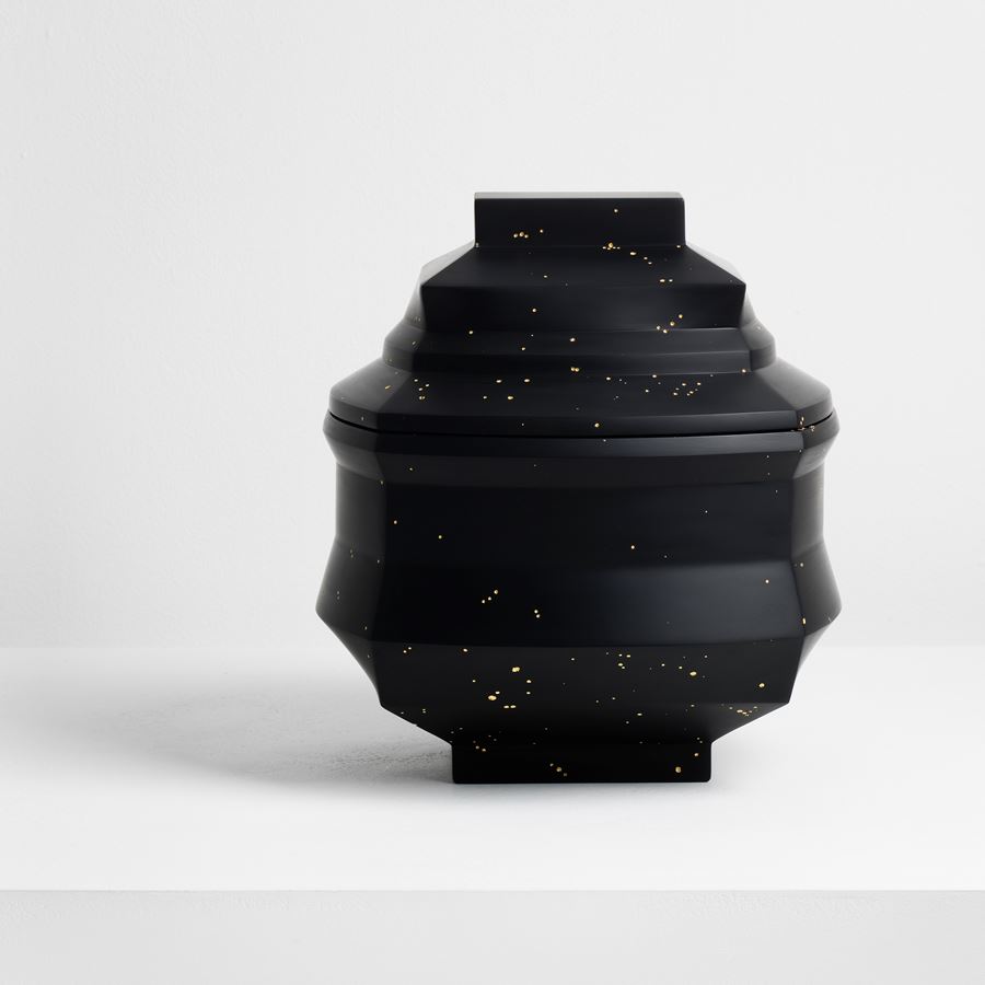 dense black box with facetted and angled sides and lid with randomly arranged recessed small holes all over the surface filled with 23.5 carat gold hand made from cast glass