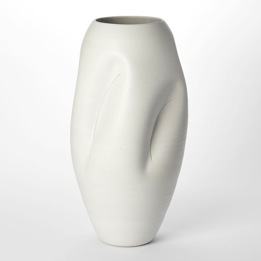 tall oval milky white vessel with soft crevasse indentations and curved thin brancusi style slash cut marks through the surface hand made and thrown from clay