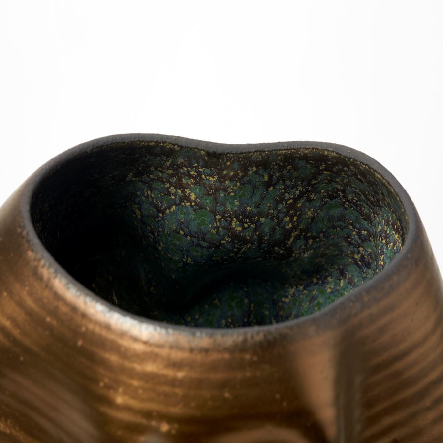 tall crumpled and wrinkled weathered bronze gold coloured vessel with rich dark turquoise green and blue speckled interior and made from glazed white st thomas clay