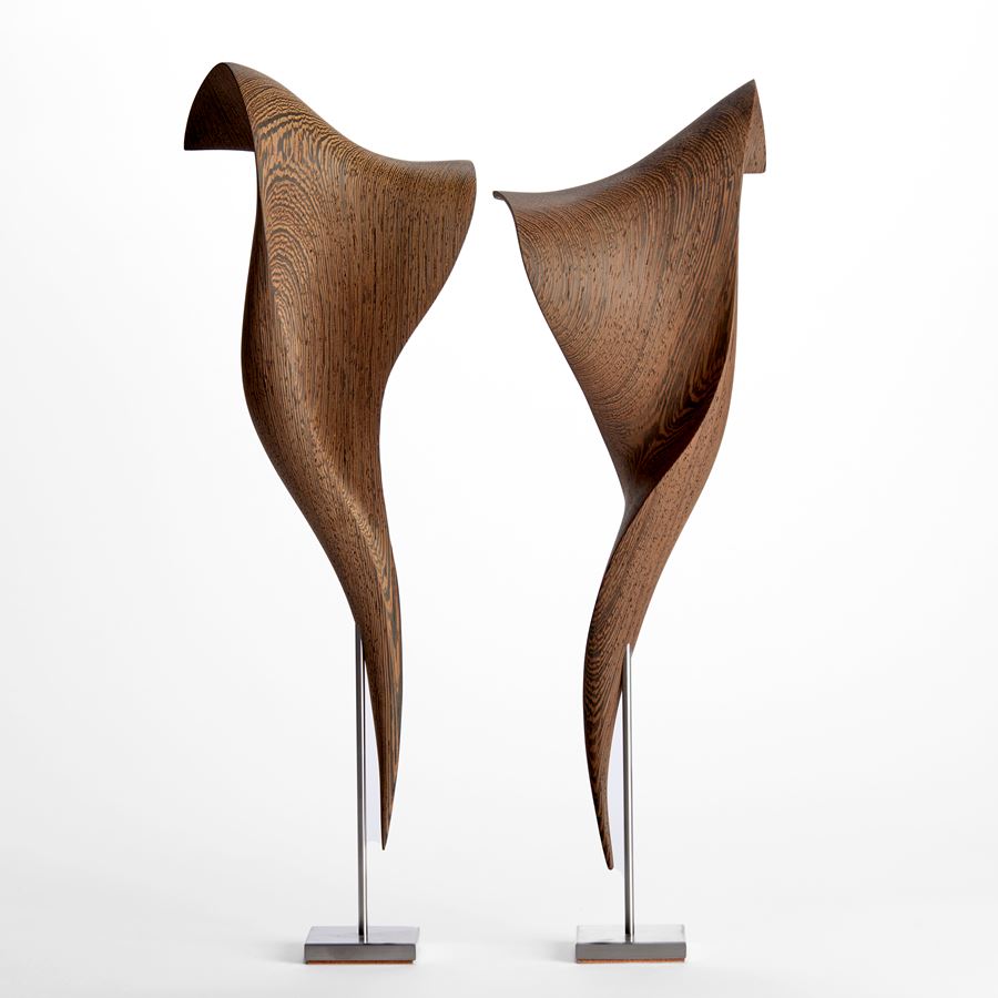 curled Wengé wood sculpture with the appearance of a fluttering and falling piece of silk with patterned wood grain texture on stainless steel stand