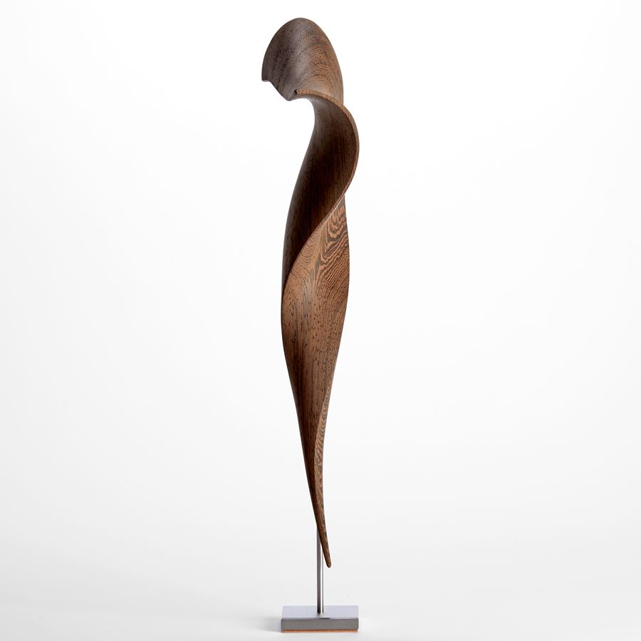 curved wenge wood sculpture with the appearance of a tapered curling piece of parchment held aloft on a stainless steel base