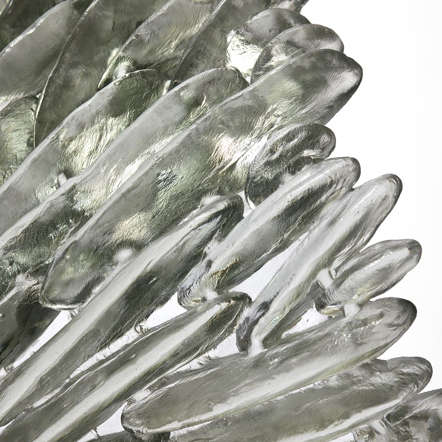 clear and grey stood organic looped drooping form with one side flat and shiny the other covered in raised fins like the gills of a mushroom hand made from cast glass