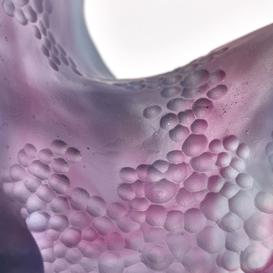 standing abstract organic pink and dark lilac purple sculpture with frilled edges and areas with scaled surface cut patterns hand made from cast glass