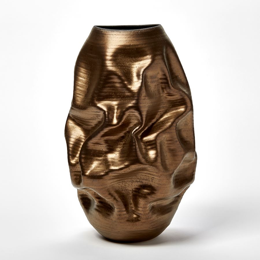bronze gold crunched wrinkled and ridged oval standing vase with oval opening and blue starburst pattern inside handmade from ceramic