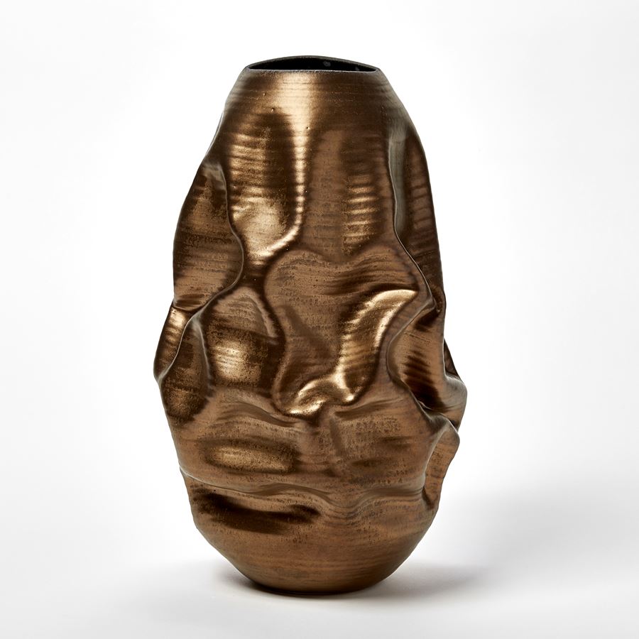 bronze gold crunched wrinkled and ridged oval standing vase with oval opening and blue starburst pattern inside handmade from ceramic