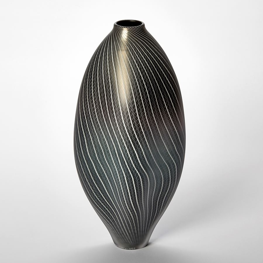 black and pewter amorphic shaped vessel with small top opening and fine white line lace like pattern covering the surface hand made from glass