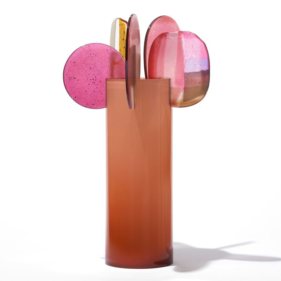 opaque orange cylinder with five rounded finials overlapping and perched on the top edge with abstract patterns in pink gold white and clear hand made from blown and fused glass