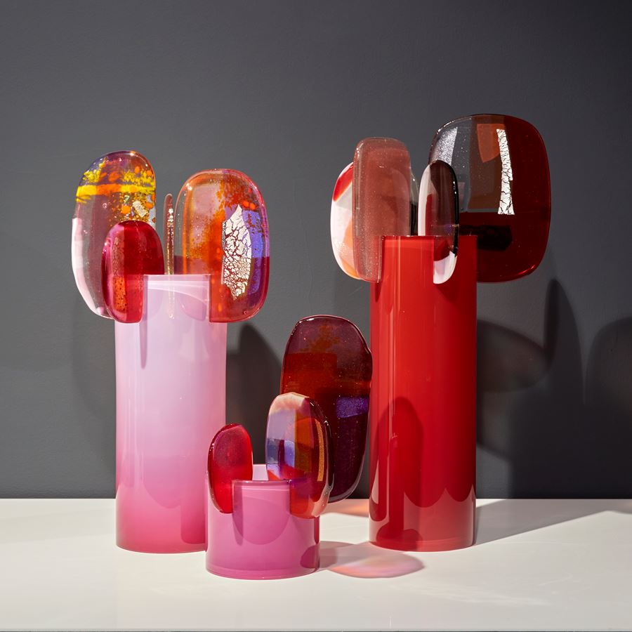 rich oxblood red cylinder with five finials perched on the rim with abstract patterns in aubergine red and pink hand made from blown and fused glass by amy cushing