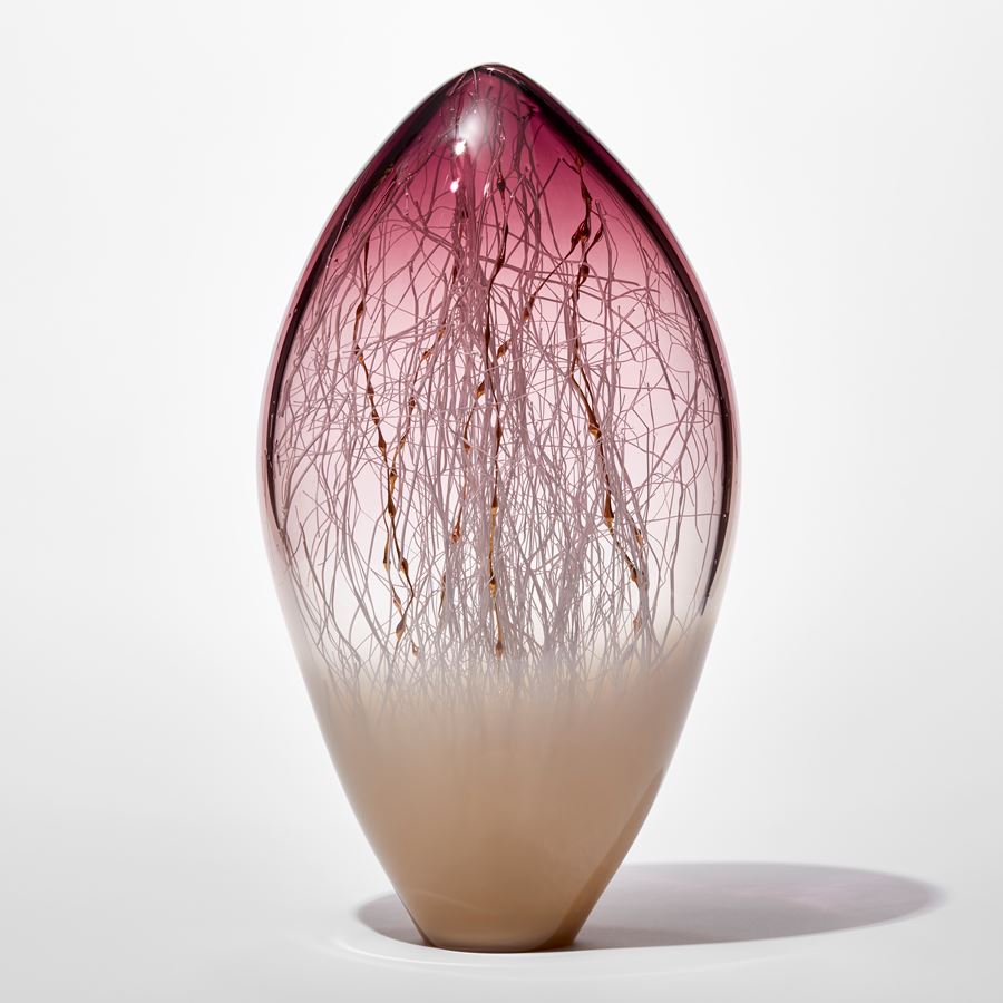clear and opaque tall rounded glass sculpture with soft pointed top with beige base and aubergine purple top with fine white canes traversing and trapped inside mixed with gold ones with bulbous sections like seaweed