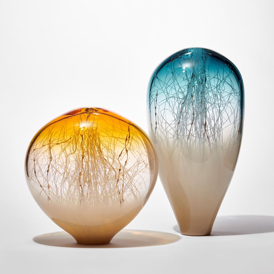 tall transparent and opaque glass sculpture with round top in soft light bronze base and rich blue with fine white canes traversing and trapped inside mixed with gold ones