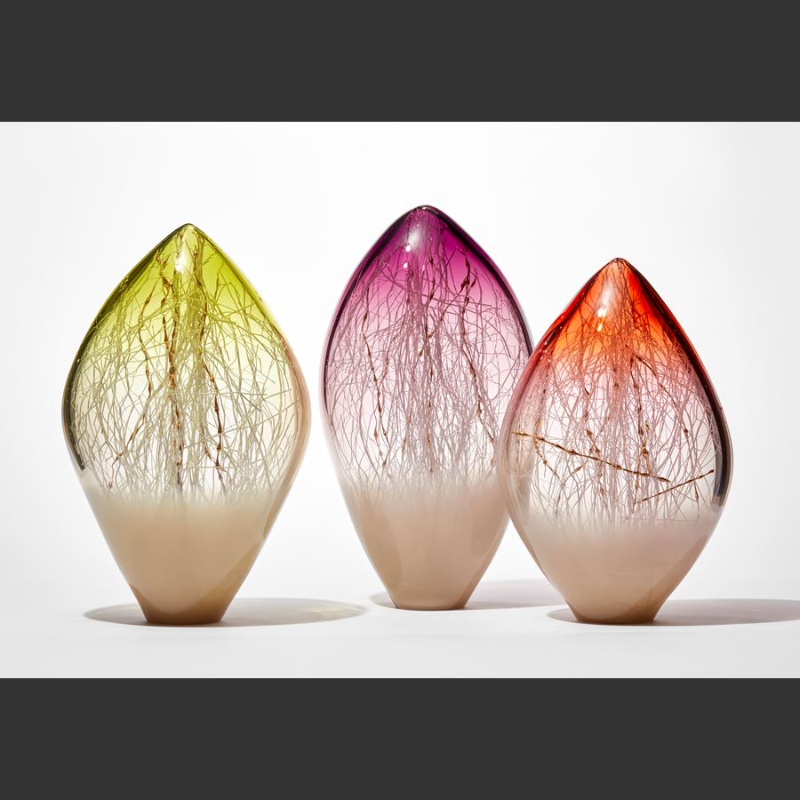opaque and transparent pointed ovoid standing glass sculpture with soft bronze base and rich orange red top with fine white canes trapped inside intermingled with gold ones with bulbous sections