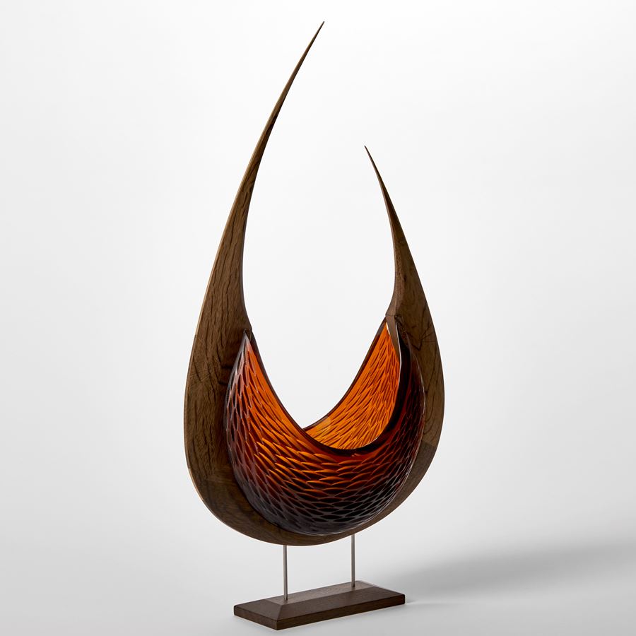 stylised viking ship with curved oak hull and two sections of rich dark amber textured hand blown glass held aloft on a stainless steel and wood base 