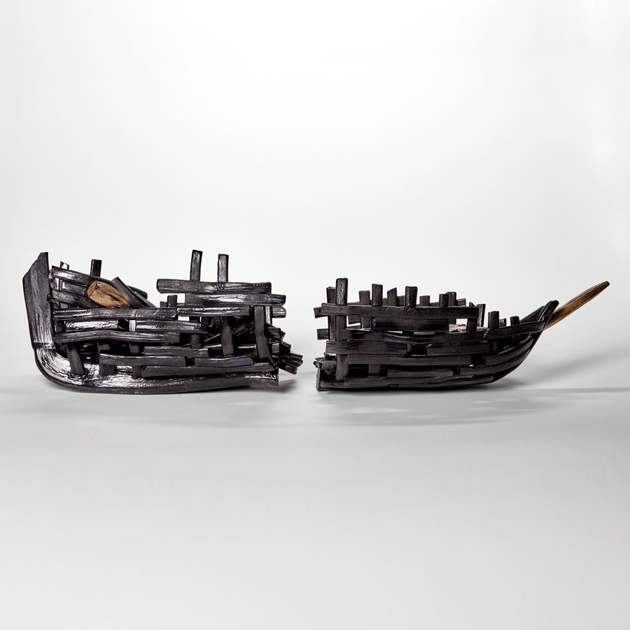 black and bronze hued glass sculpture resembling two halves of a sunken aged ship wreck with split hull and old sea worn timbers