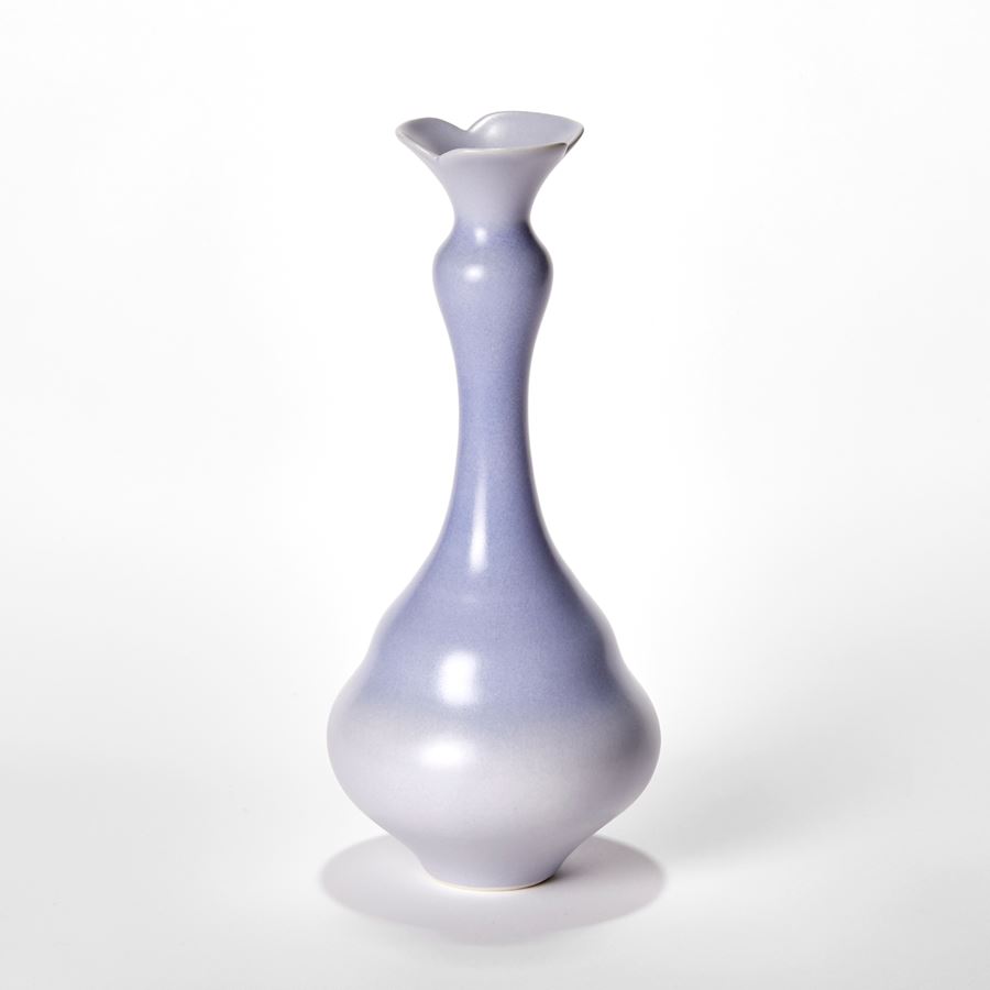 set of three porcelain vases in soft lilac purple each with wide rounded bases narrowing to long elegant necks each with abstract floral opening rims