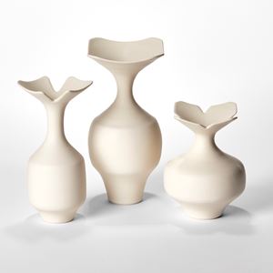 trio of porcelain vases with angular rounded bases long necks and squared flaring rims in a soft butter coloured finish