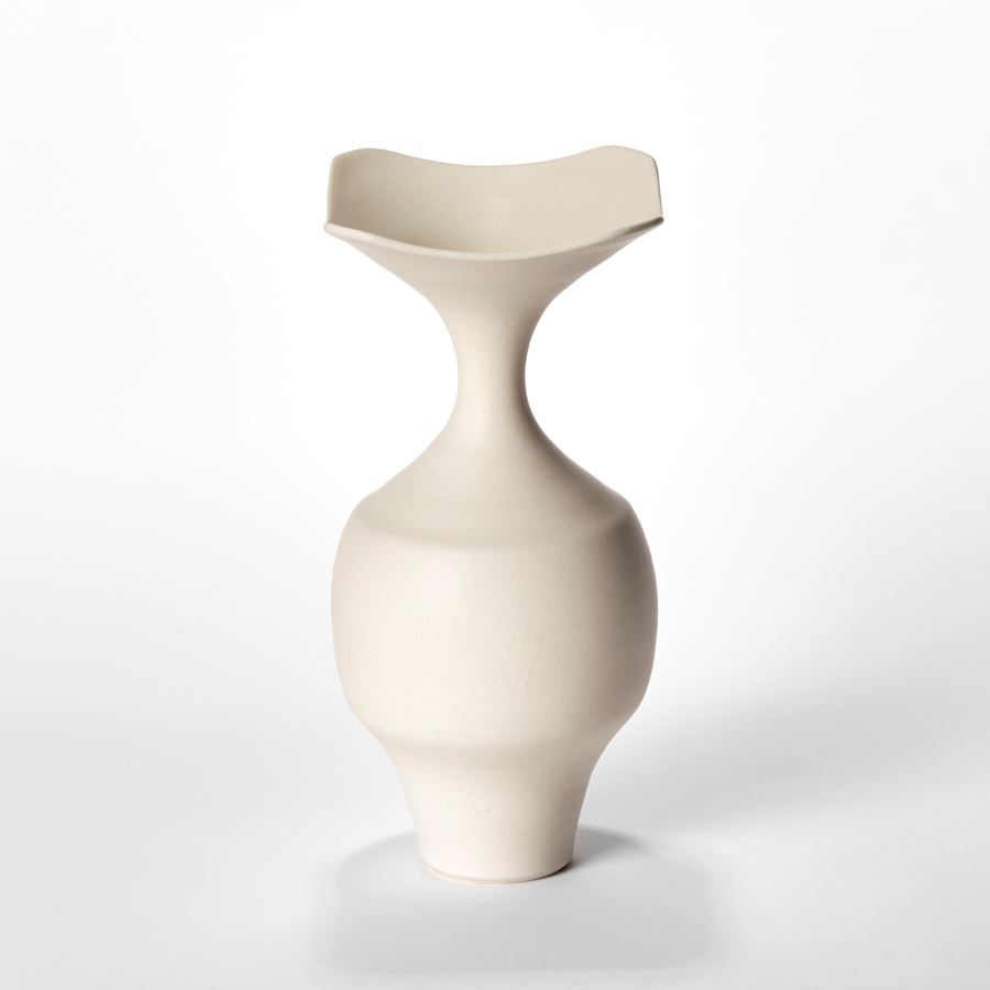 trio of porcelain vases with angular rounded bases long necks and squared flaring rims in a soft butter coloured finish
