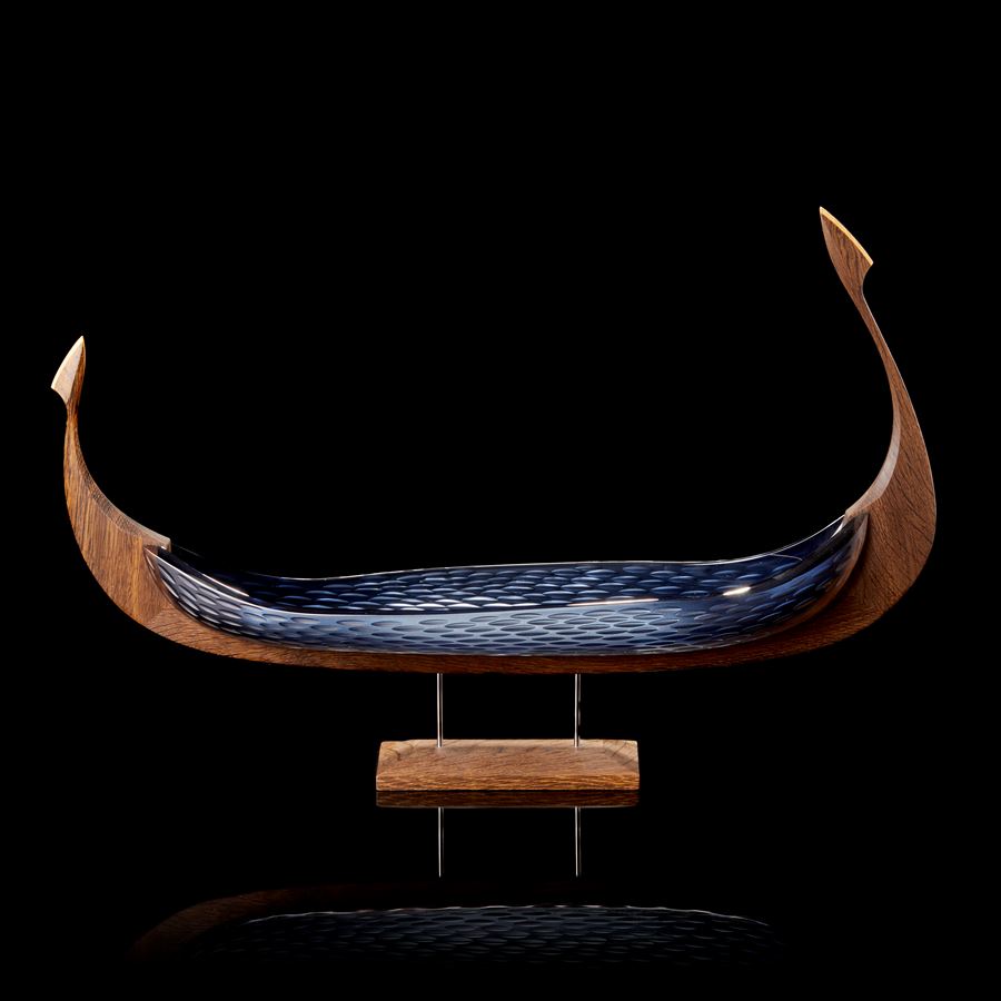 dark oak and opaque cut blue glass hulled viking ship with repeat cut texture pattern hand made and presented on a stainless steel and wooden base