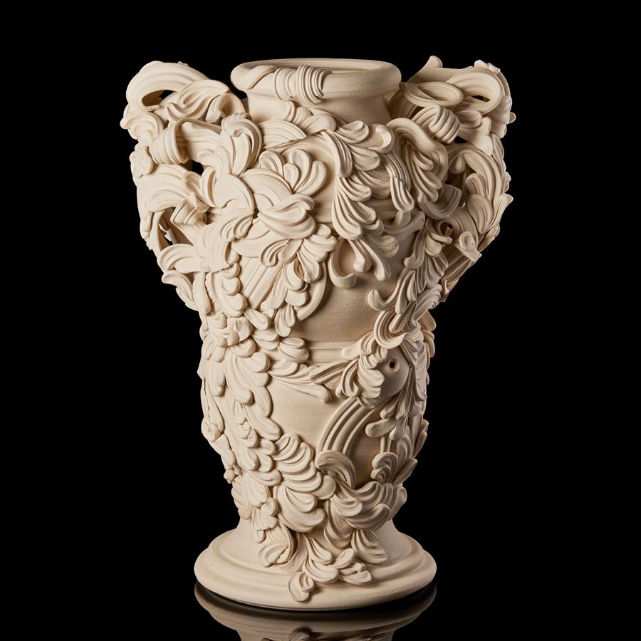 tall architectural ceramic sculptural vessel with handles with the appearance of weather worn sandstone covered in busy adornment of swirls and flourishes hand made from white st thomas clay