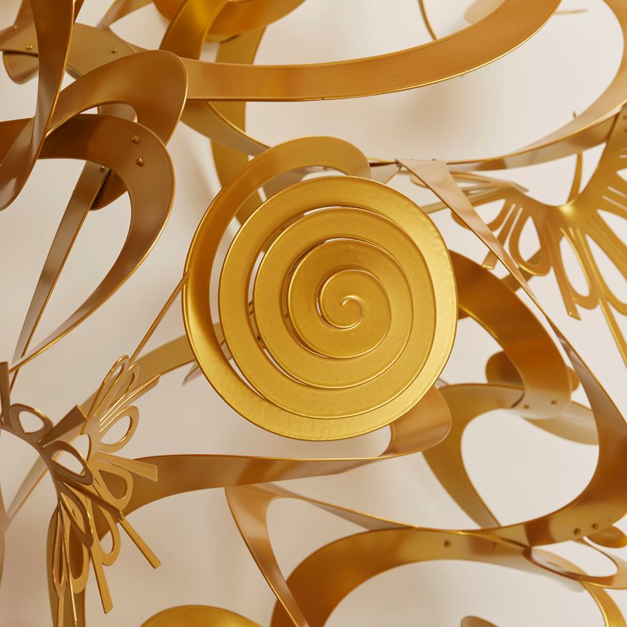 organically rounded and domed wall installation created from rings loops swirls and ribbons of matt gold power coated aluminium with the material equalling in quantity to the negative space within the artwork