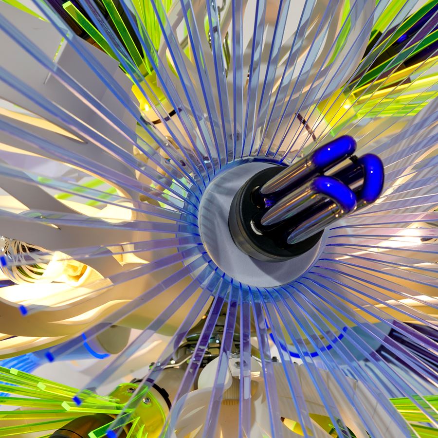 hanging sculptural light in white blue and green which resembles alien botany a vibrant mix of graphic repetitive organic three dimensional shapes with cutout sections and fronds made from acrylic with ultraviolet lightbulbs