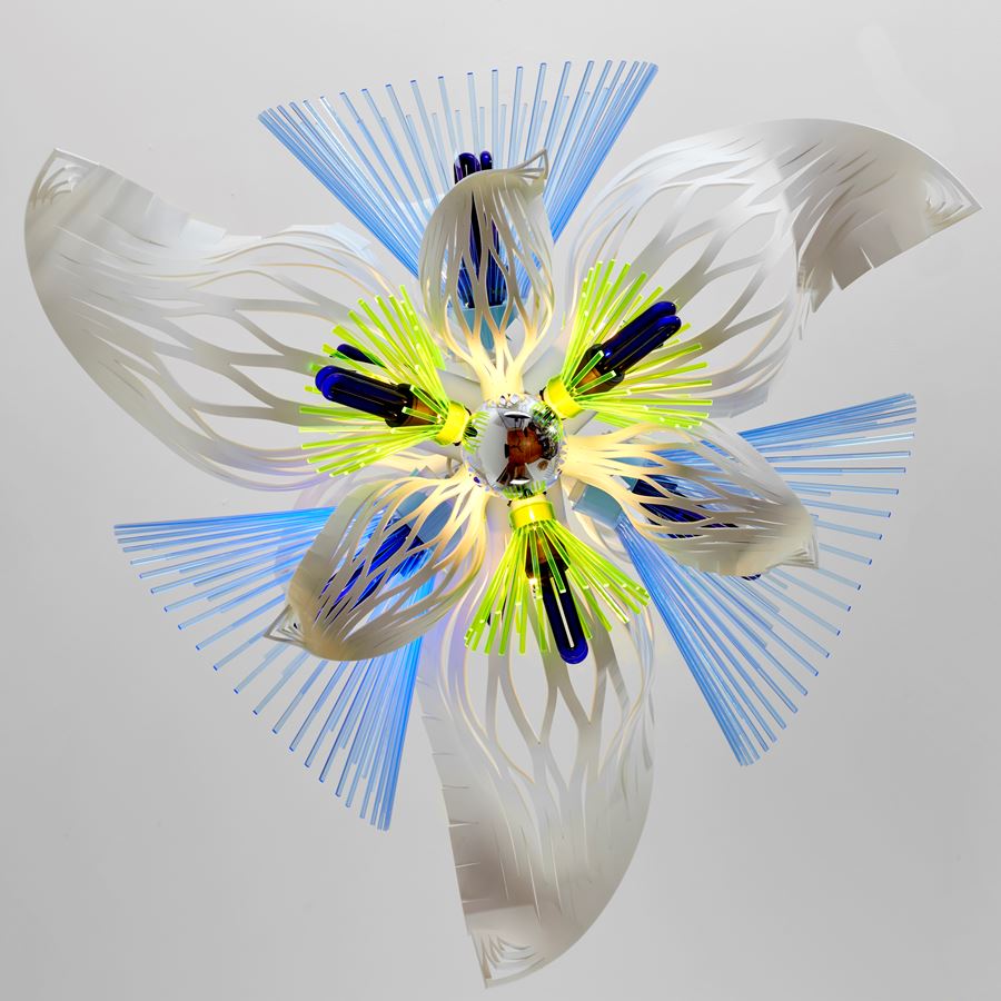 hanging sculptural light in white blue and green which resembles alien botany a vibrant mix of graphic repetitive organic three dimensional shapes with cutout sections and fronds made from acrylic with ultraviolet lightbulbs