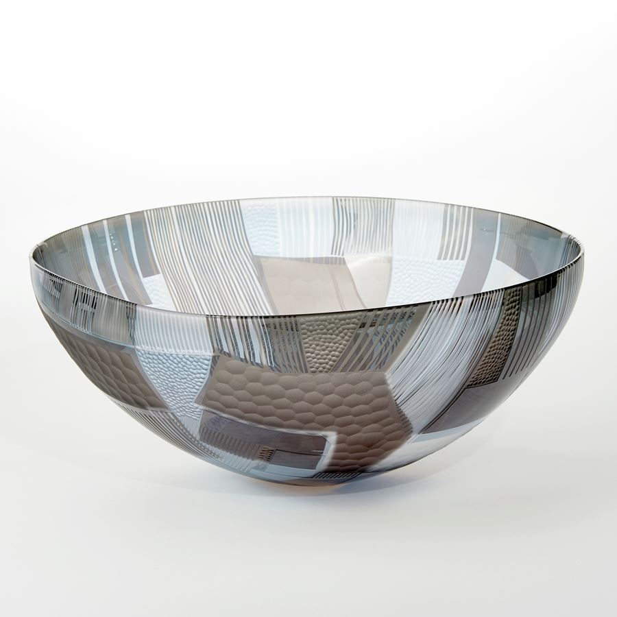 grey clear and aqua wide open bowl with cut abstract landscape patterns on both the interior and exterior surfaces hand made from glass