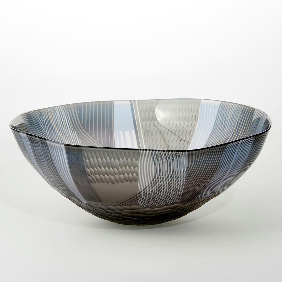 round shallow translucent grey and steel blue bowl with small foot and covered in abstract landscape inspired patterns handblown from glass