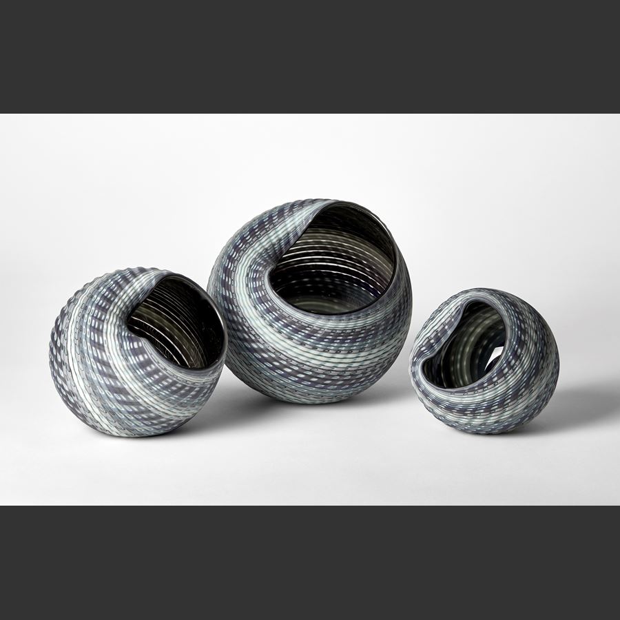textured and woven in appearance shell like vessel with matt exterior and shiny interior with bands of colour in steel blue jade grey and aqua hand made from glass